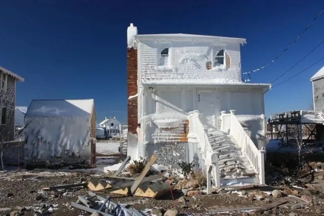 Cedar Point home cased in wind-driven ice with storm debris in the yard