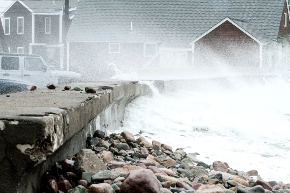 Waves overtopping the seawall and washing rocks onto the road during a nor'easter
